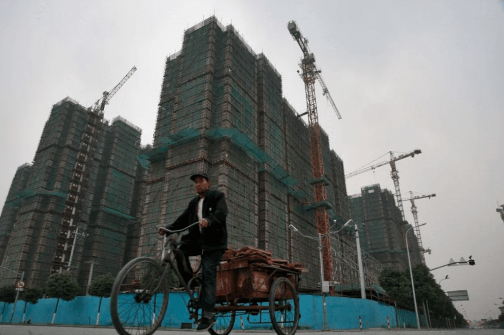 A man rides his rickshaw past a residential development in Shanghai, China. (In Pictures Ltd./Corbis via Getty Images)